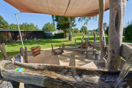 Hier wird geplanscht, gematscht und herzlich gelacht. Unsere Wassermatschanlage aus robusten Robinienholz lädt kleine Wirbelwinde ein, spielerisch die Welt des Wassers zu entdecken und dank Sonnensegel sicher im Schatten zu bleiben.