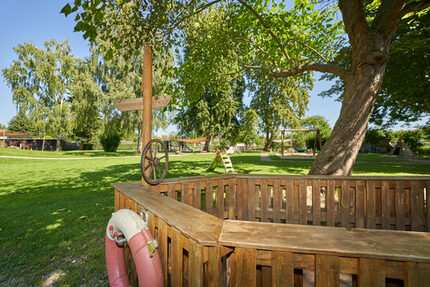 Hier hisst die Kita-Crew die Segel. Unser gemeinsam mit Eltern gebautes Piratenschiff macht jedes Kind zum mutigen Entdecker. Dahinter breitet sich unser weitläufiges Gartengelände aus. Ein weites Abenteuerland für kleine Fantasiepiraten.